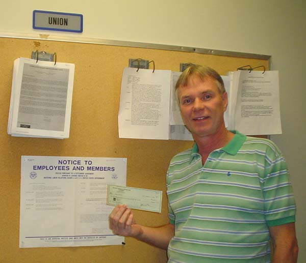 Randy holding his check in front of Federal Violation Notice 